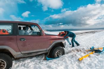 Männer schieben Auto aus Schnee