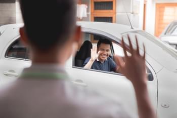 Mann im Mietwagen winkt