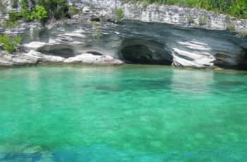 Türkisblaues Wasser vor Kalksteinhöhlen
