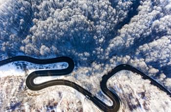 Blick auf Straße mit Kurven im Winterwald